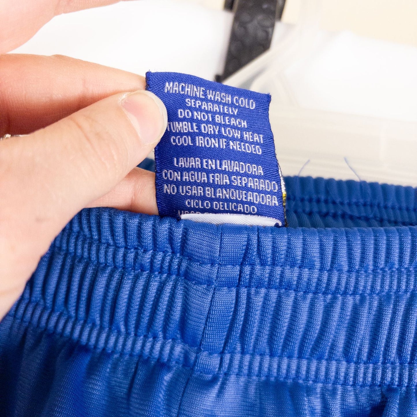 Blue DC Athletics track pants with white stripes down sides hanging on hanger front and back views with closeups of details image 12