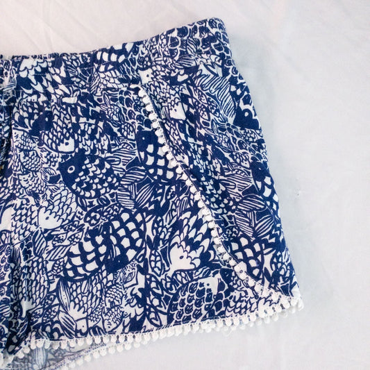 Lily Pullitzer blue fish print lounge shorts with pom pom trim and drawstring waistband laid flat image 2
