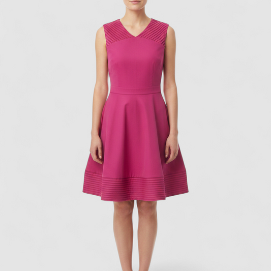 Pink sleeveless dress with sheer striped mesh panels on neckline and hem laid flat on wood floor on model