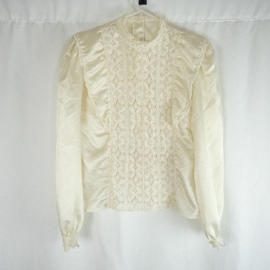 Vintage ivory satin blouse featuring intricate lace detailing on front and cuffs displayed on hanger