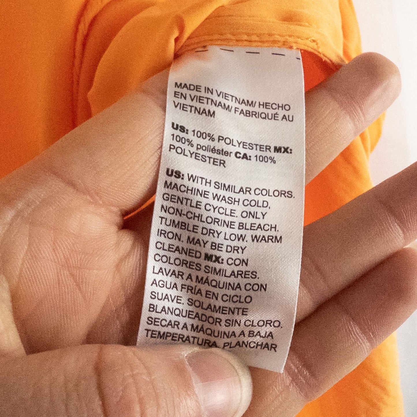 Bright orange long sleeve tunic blouse by Chicos hanging on a white hanger, showing front, back, sleeves, and fabric texture with small pinprick flaw image 8