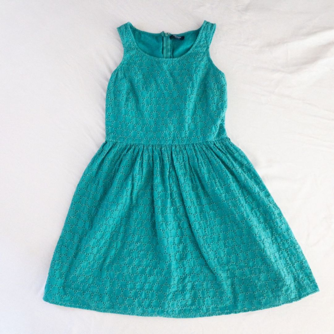 Old Navy teal green doily pattern sleeveless summer dress with gathered waist and concealed back zipper hanging on a clear hanger against a white cloth background image 12