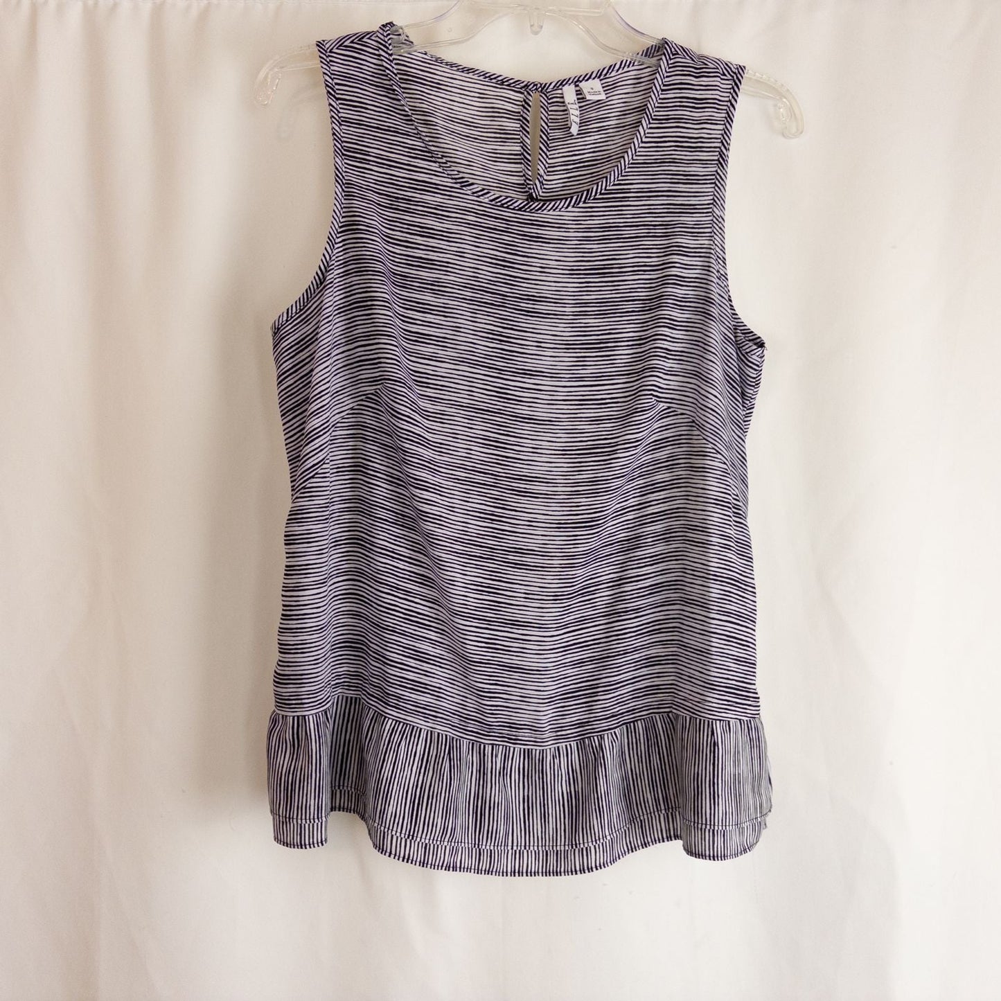 Elle black and white striped sleeveless tank top with peplum hem on clear hanger