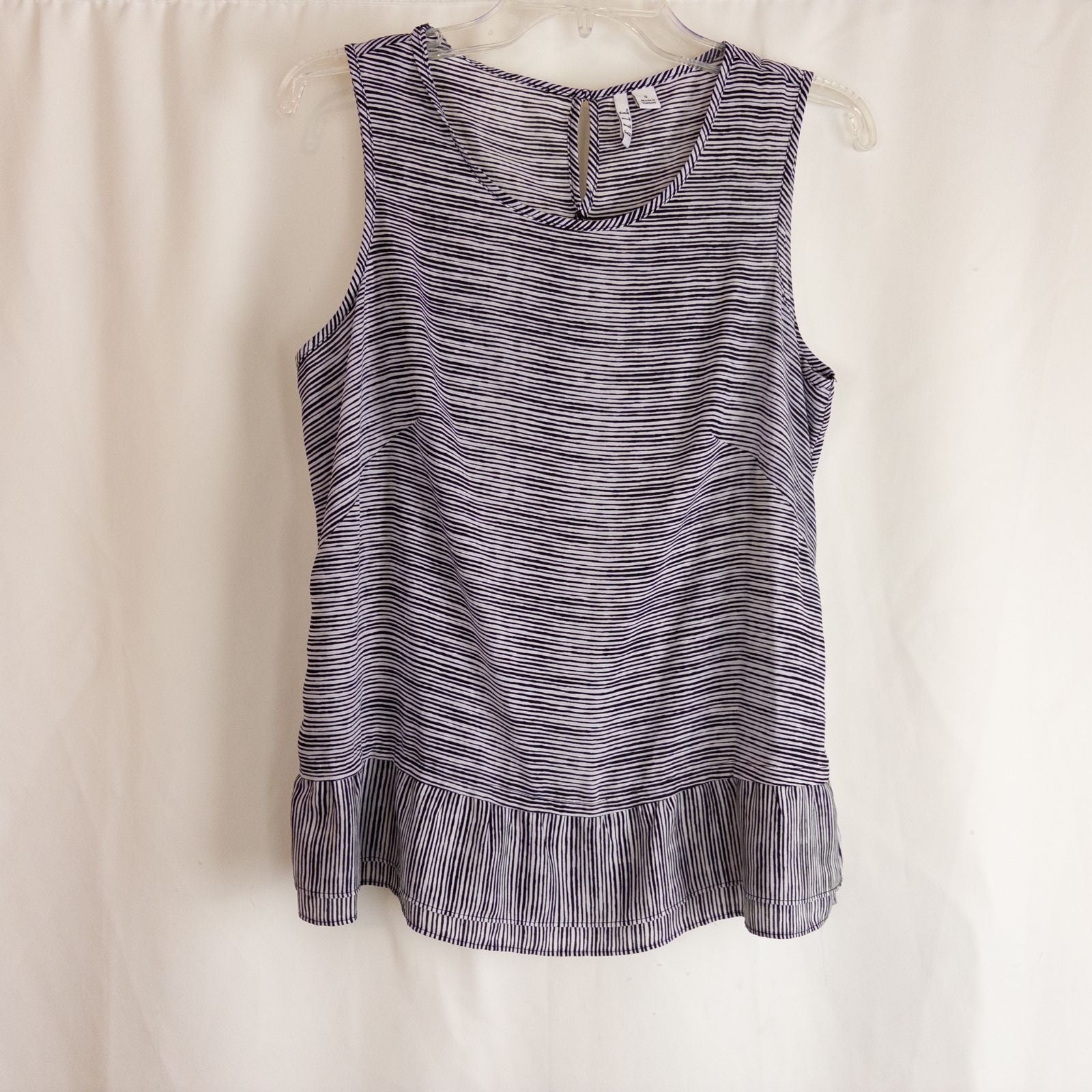 Elle black and white striped sleeveless tank top with peplum hem on clear hanger