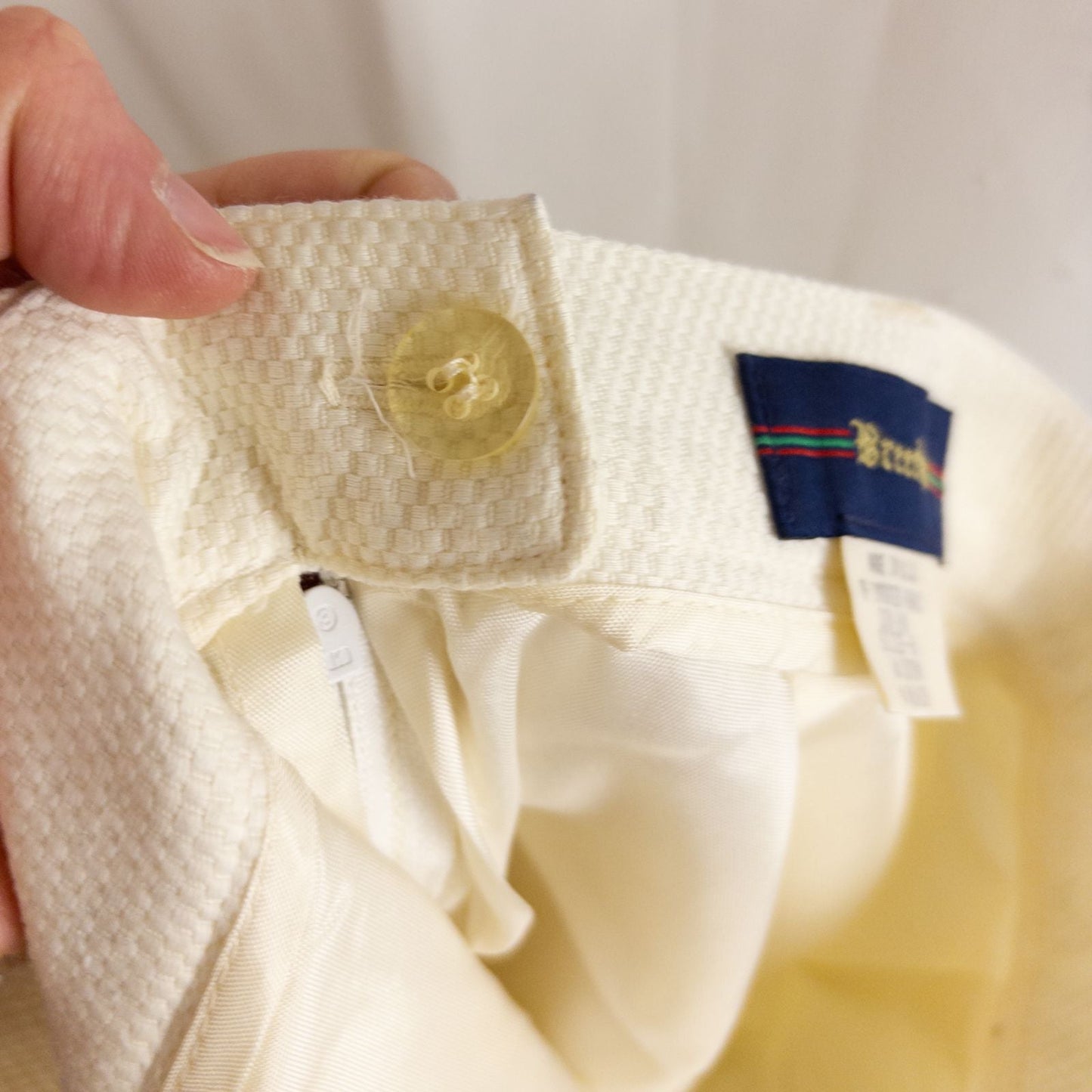 Vintage ivory pique pencil skirt with side zipper and button tab detail hanging on a hanger image 5