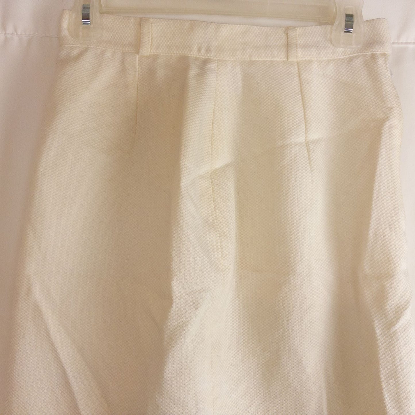 Vintage ivory pique pencil skirt with side zipper and button tab detail hanging on a hanger image 2