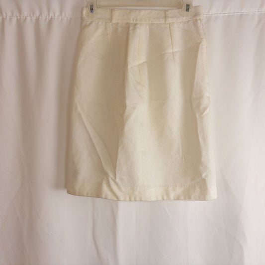 Vintage ivory pique pencil skirt with side zipper and button tab detail hanging on a hanger