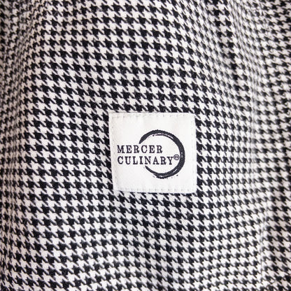 Mercer Culinary black and white houndstooth high rise pants in womens small size hanging on plastic hanger against white background showing front, side pockets, and back Mercer Culinary logo image 8