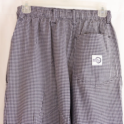 Mercer Culinary black and white houndstooth high rise pants in womens small size hanging on plastic hanger against white background showing front, side pockets, and back Mercer Culinary logo image 6
