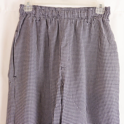 Mercer Culinary black and white houndstooth high rise pants in womens small size hanging on plastic hanger against white background showing front, side pockets, and back Mercer Culinary logo image 2