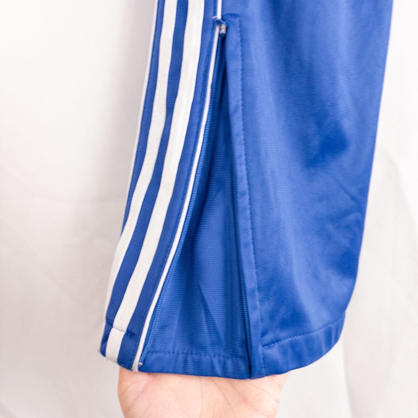 Blue DC Athletics track pants with white stripes down sides hanging on hanger front and back views with closeups of details image 9