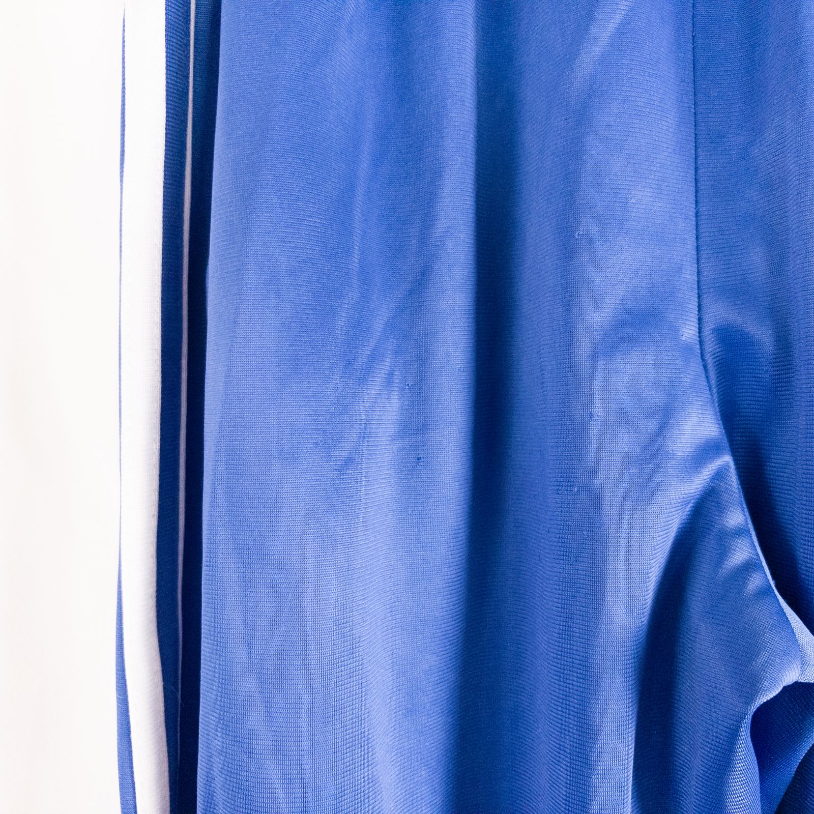 Blue DC Athletics track pants with white stripes down sides hanging on hanger front and back views with closeups of details image 6