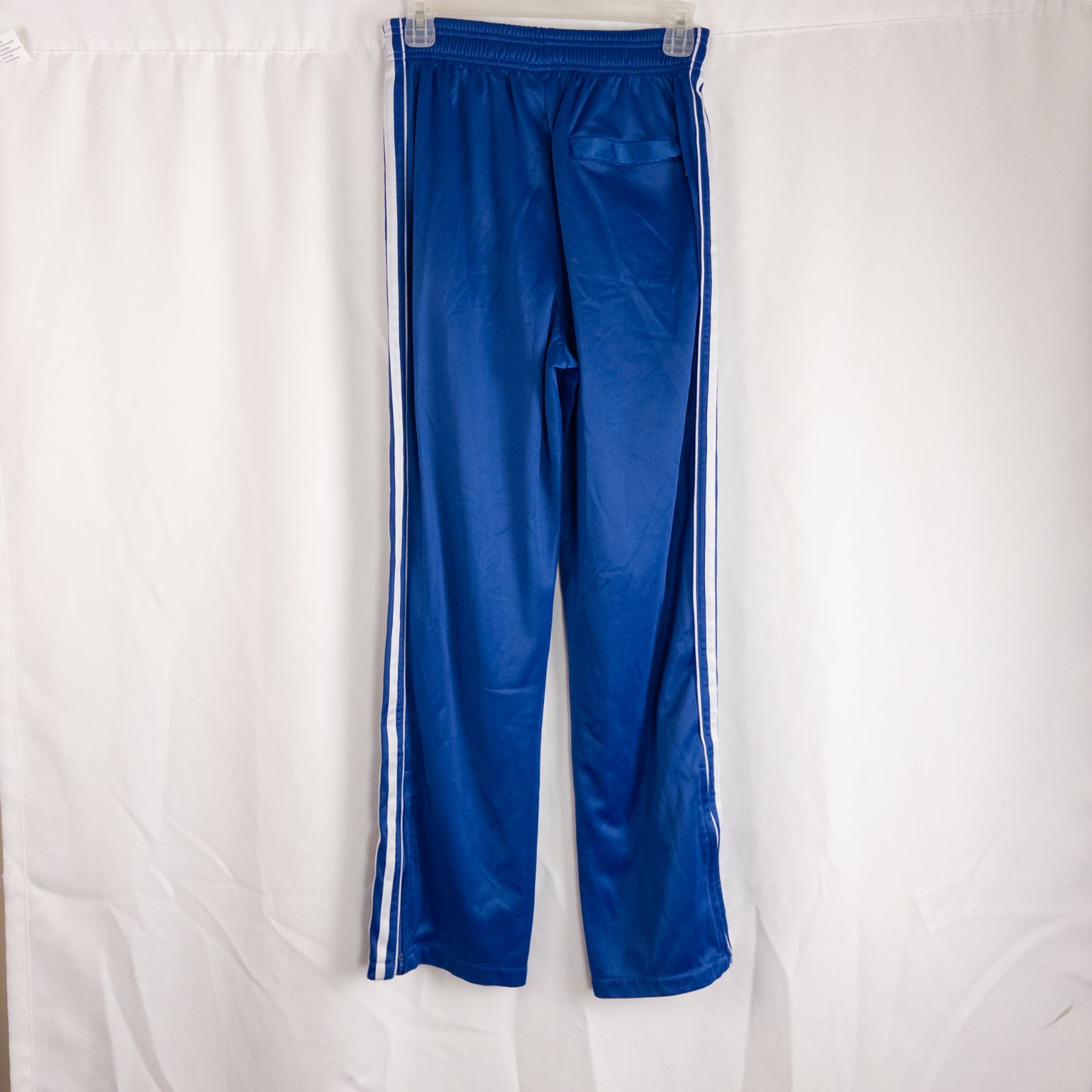 Blue DC Athletics track pants with white stripes down sides hanging on hanger front and back views with closeups of details image 3