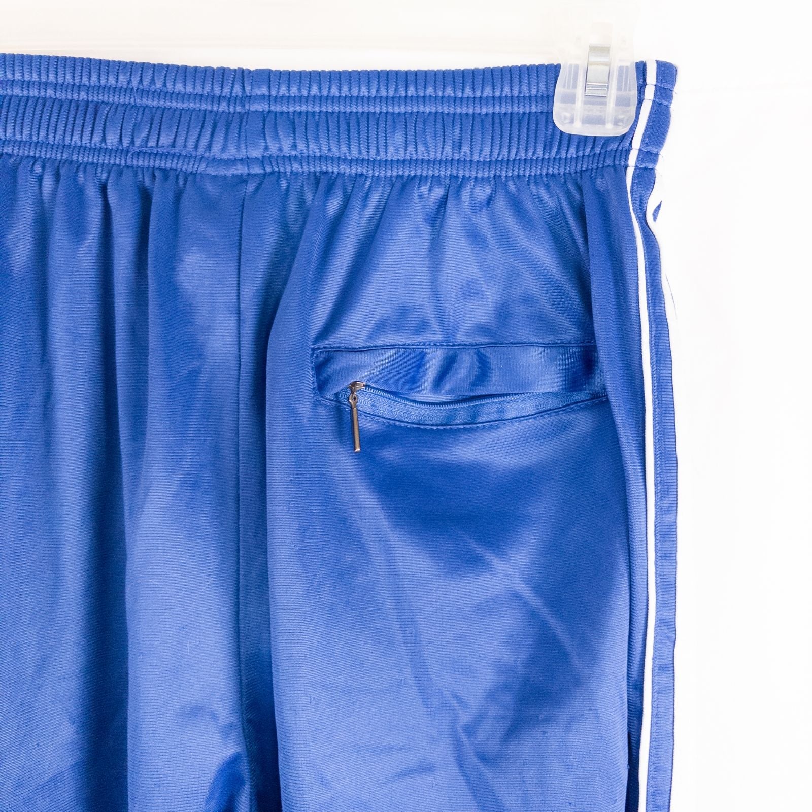 Blue DC Athletics track pants with white stripes down sides hanging on hanger front and back views with closeups of details image 5