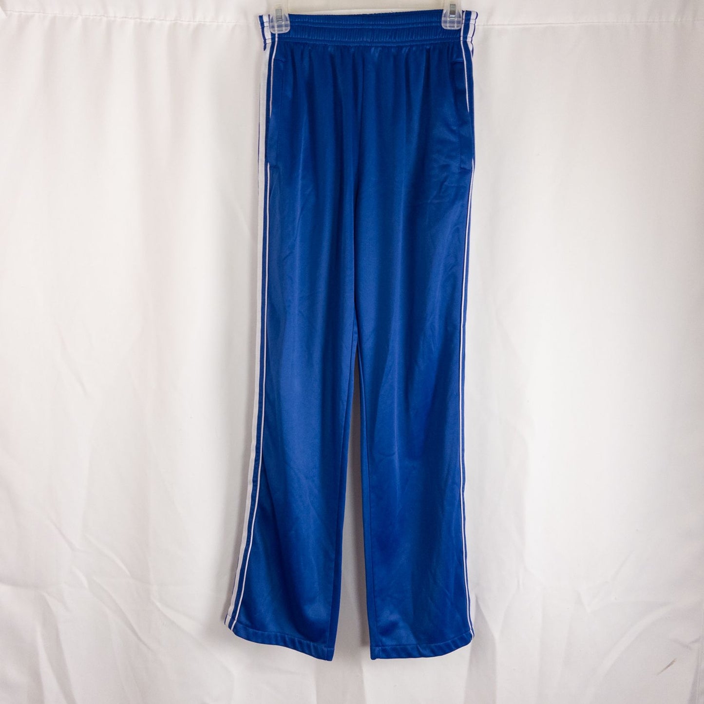 Blue DC Athletics track pants with white stripes down sides hanging on hanger front and back views with closeups of details
