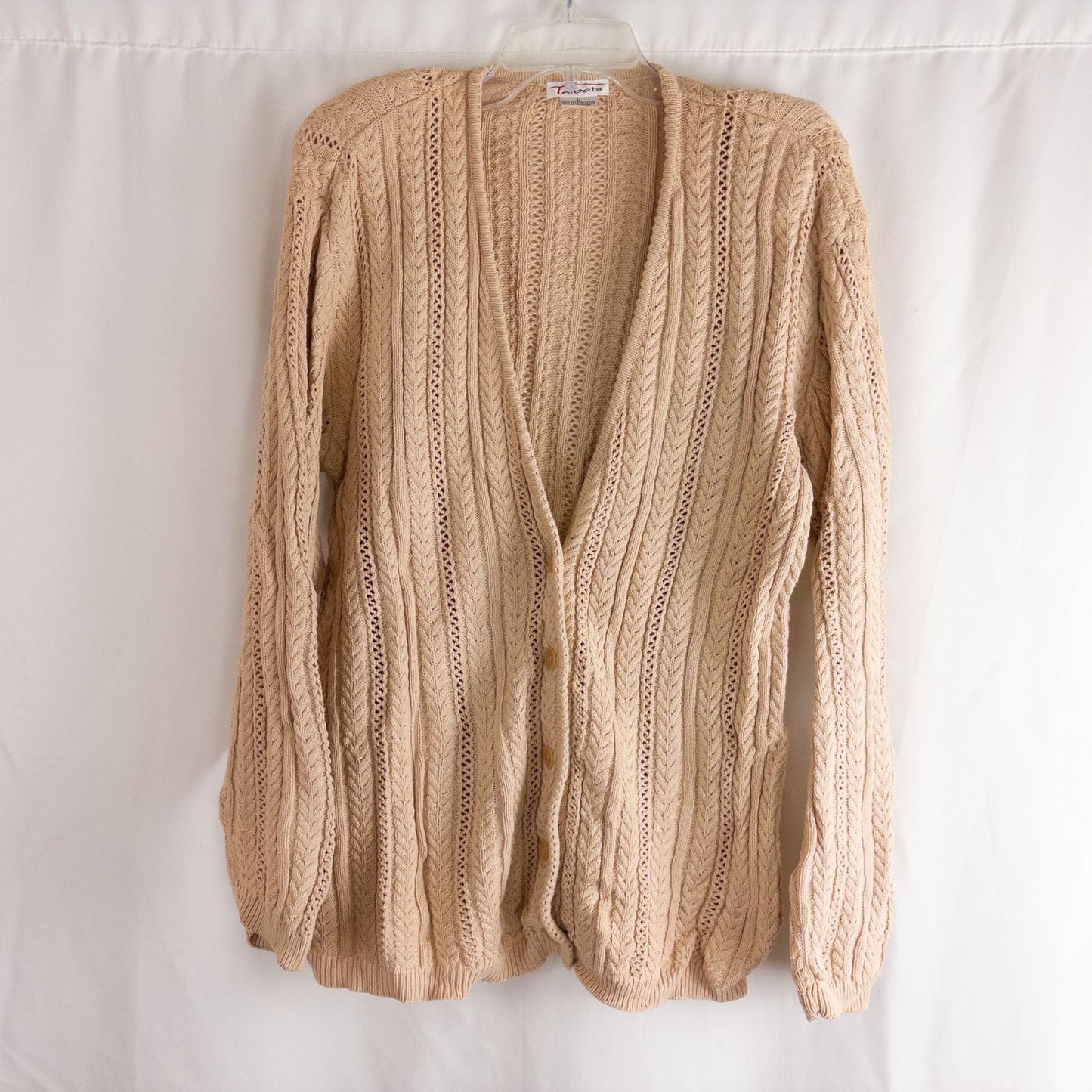 Talbots tan vintage cable knit cardigan sweater with button front and shoulder pads hanging on clear hanger