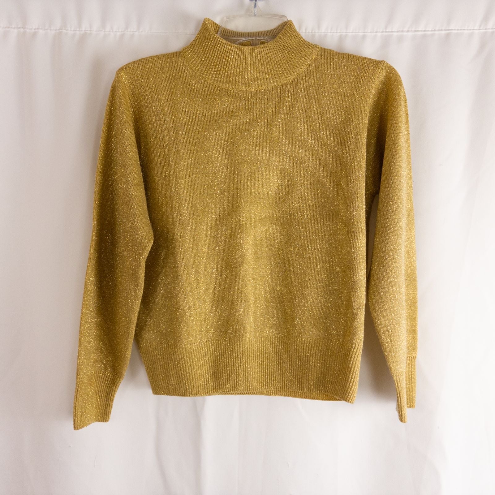 Dress Barn petite gold knit sweater with mock neck and long sleeves hung on a clear hanger