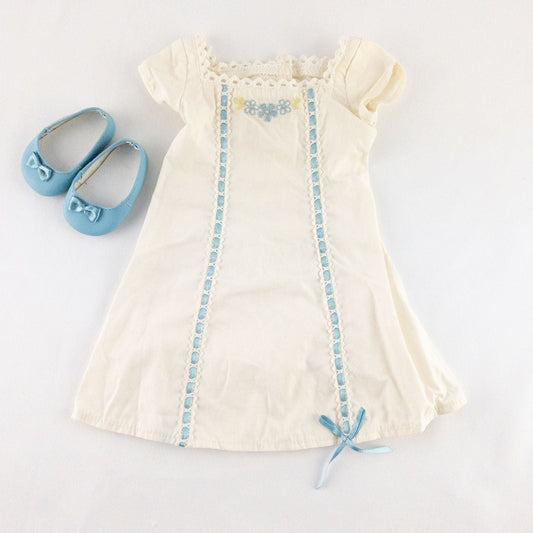 American Girl Caroline cream nightgown dress with blue ribbon detail and matching light blue doll shoes laid flat