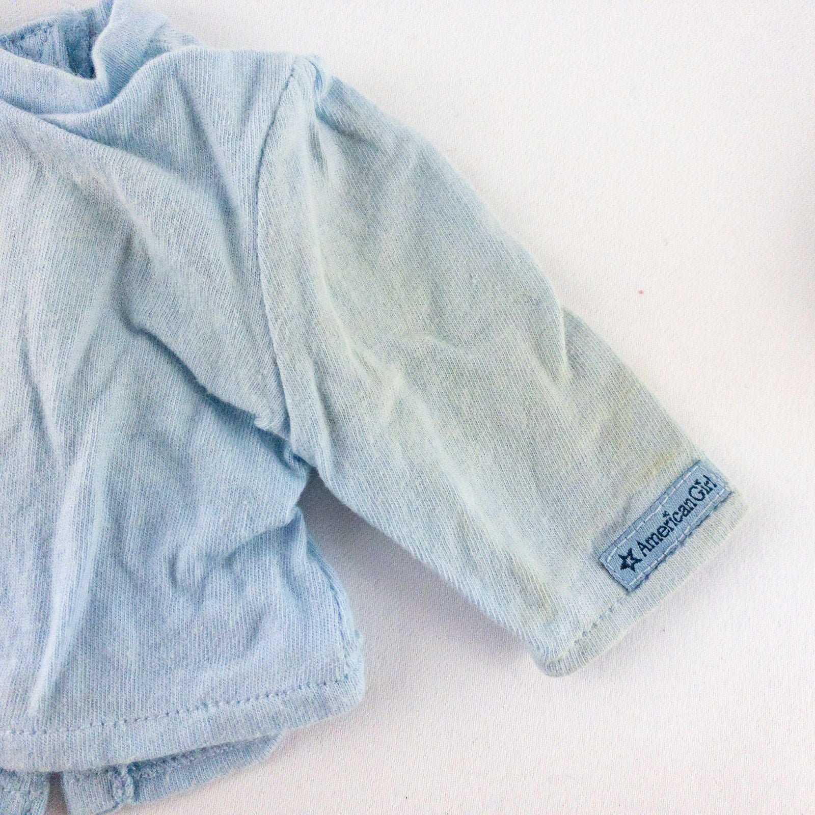 American Girl doll jumper dress outfit with blue corduroy jumper dress, faded light blue long sleeve top, and blue doll boots laid flat on white background image 9