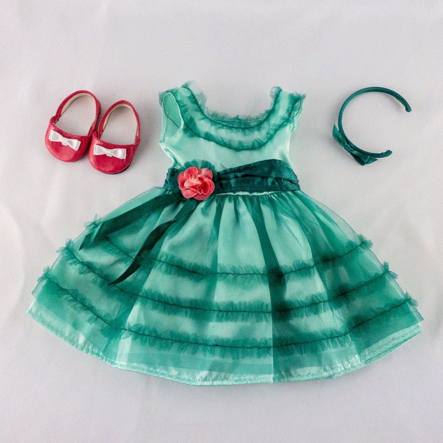 American Girl vintage green emerald doll dress with layered tulle skirt, pink flower belt detail, matching green headband, and red shoes with white bows