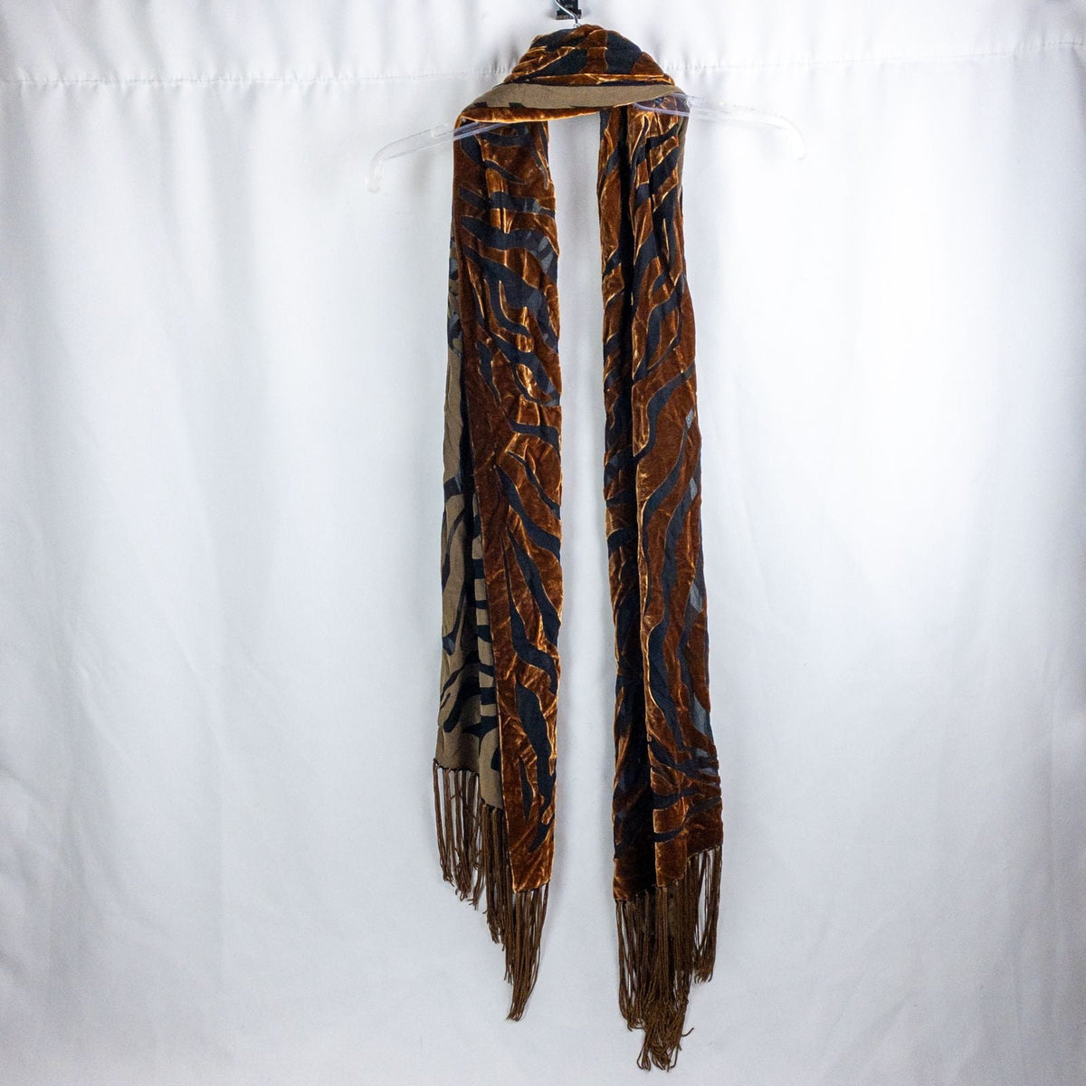 Vintage brown velvet and black sheer tassel scarf hung on clear hanger against white background