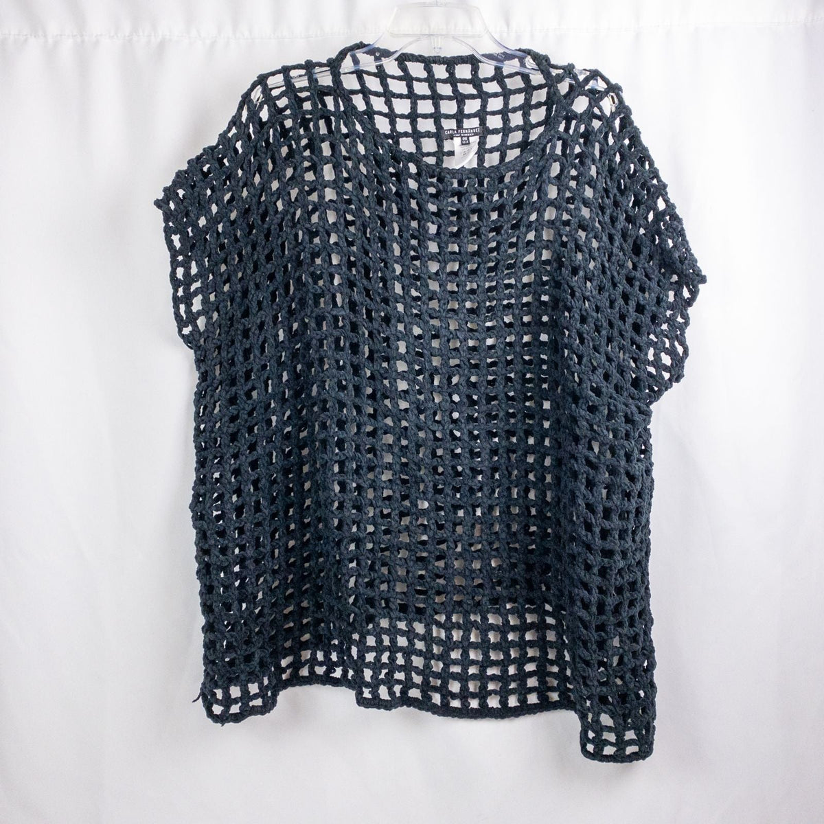 Carla Fernandez black fishnet knit rope sweater with short sleeves displayed on a hanger against a white background