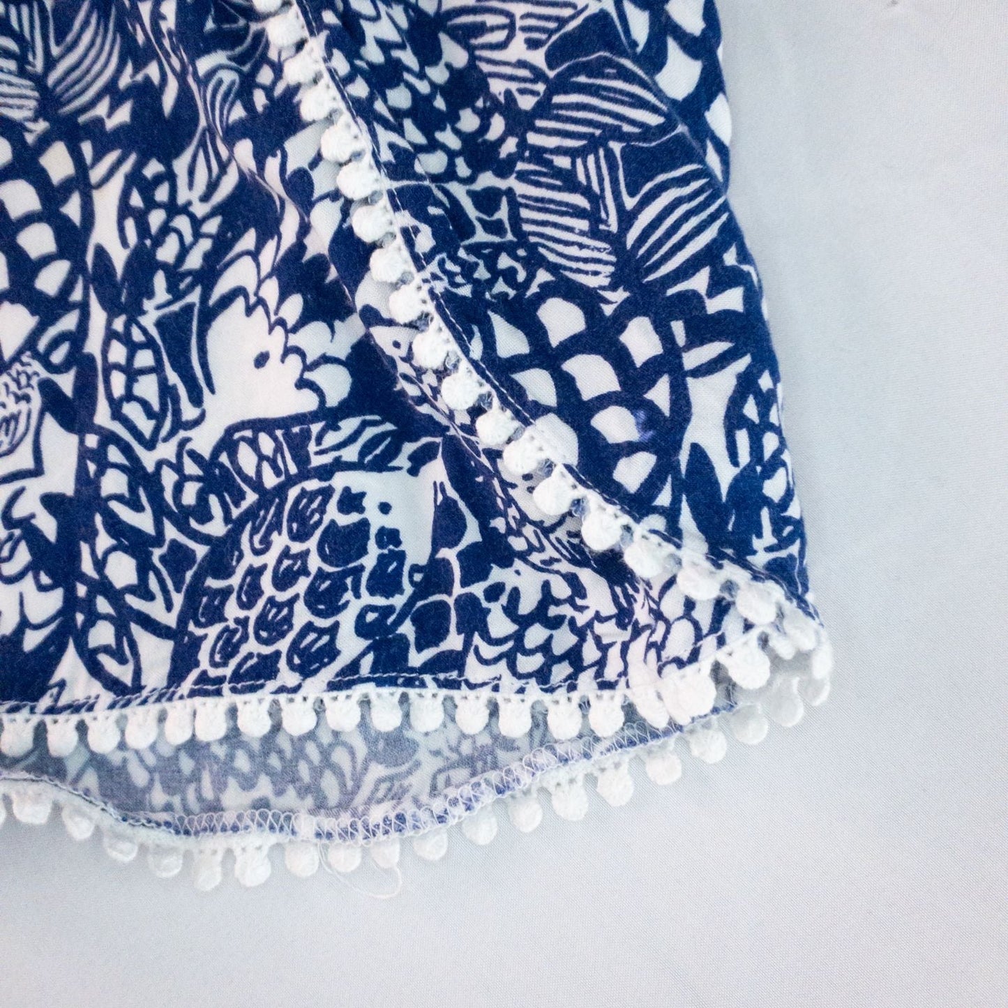 Lily Pullitzer blue fish print lounge shorts with pom pom trim and drawstring waistband laid flat image 6