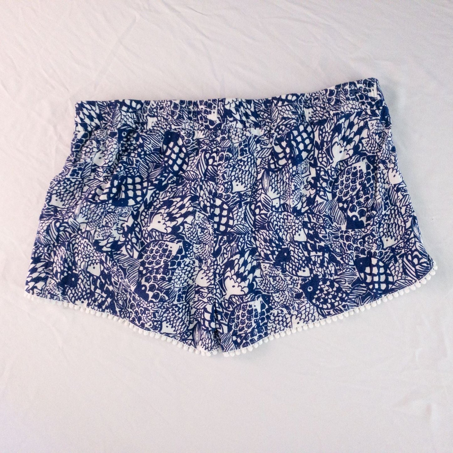 Lily Pullitzer blue fish print lounge shorts with pom pom trim and drawstring waistband laid flat image 8