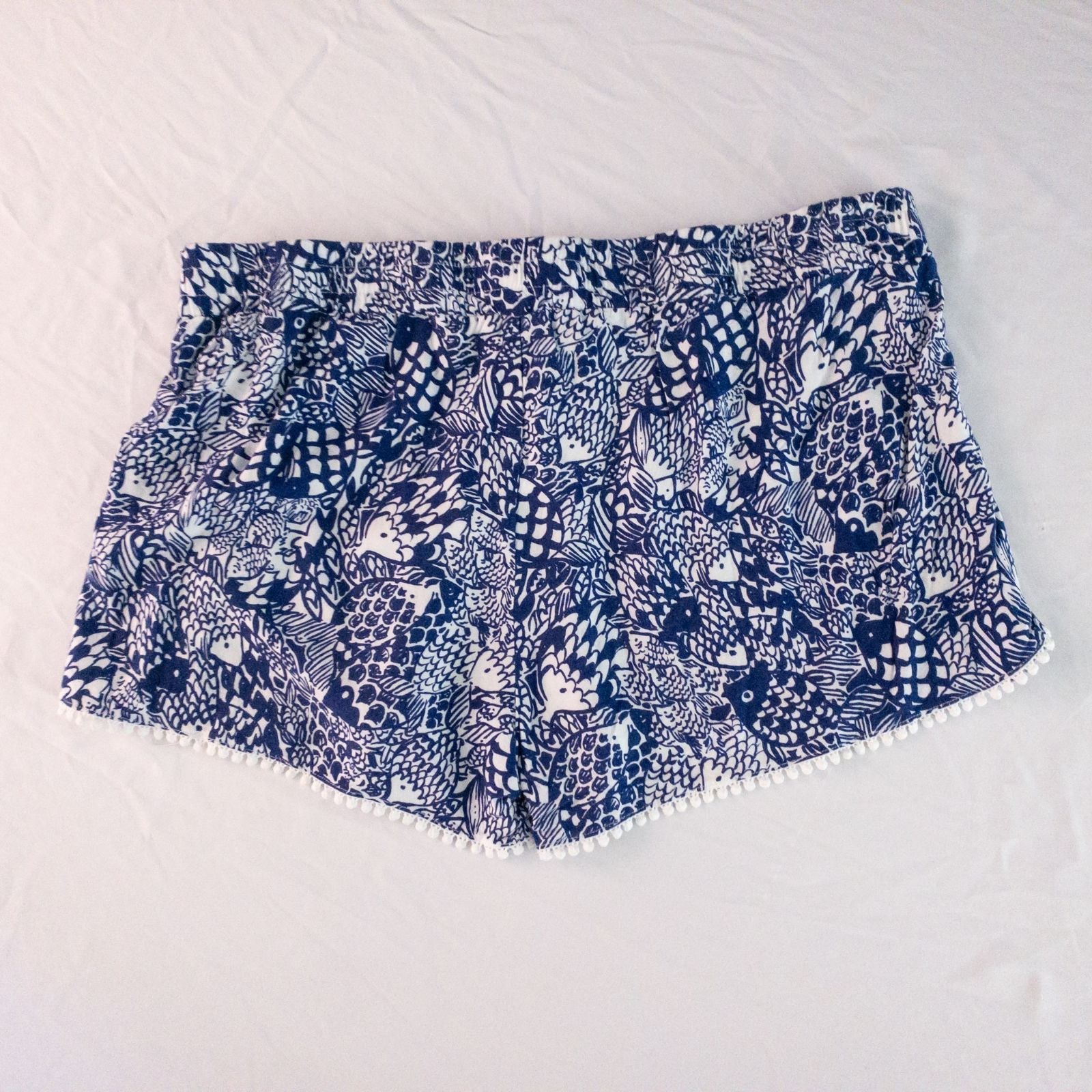 Lily Pullitzer blue fish print lounge shorts with pom pom trim and drawstring waistband laid flat image 8