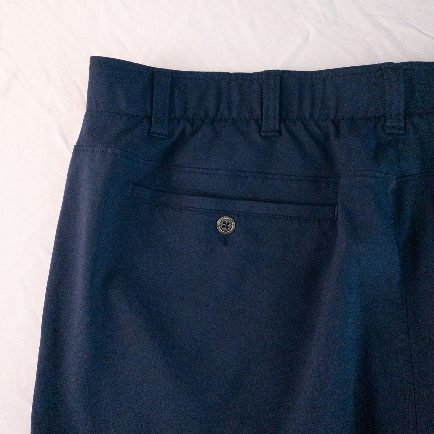Under Armour navy men's shorts laid flat showing front and back views with button and logo details image 7