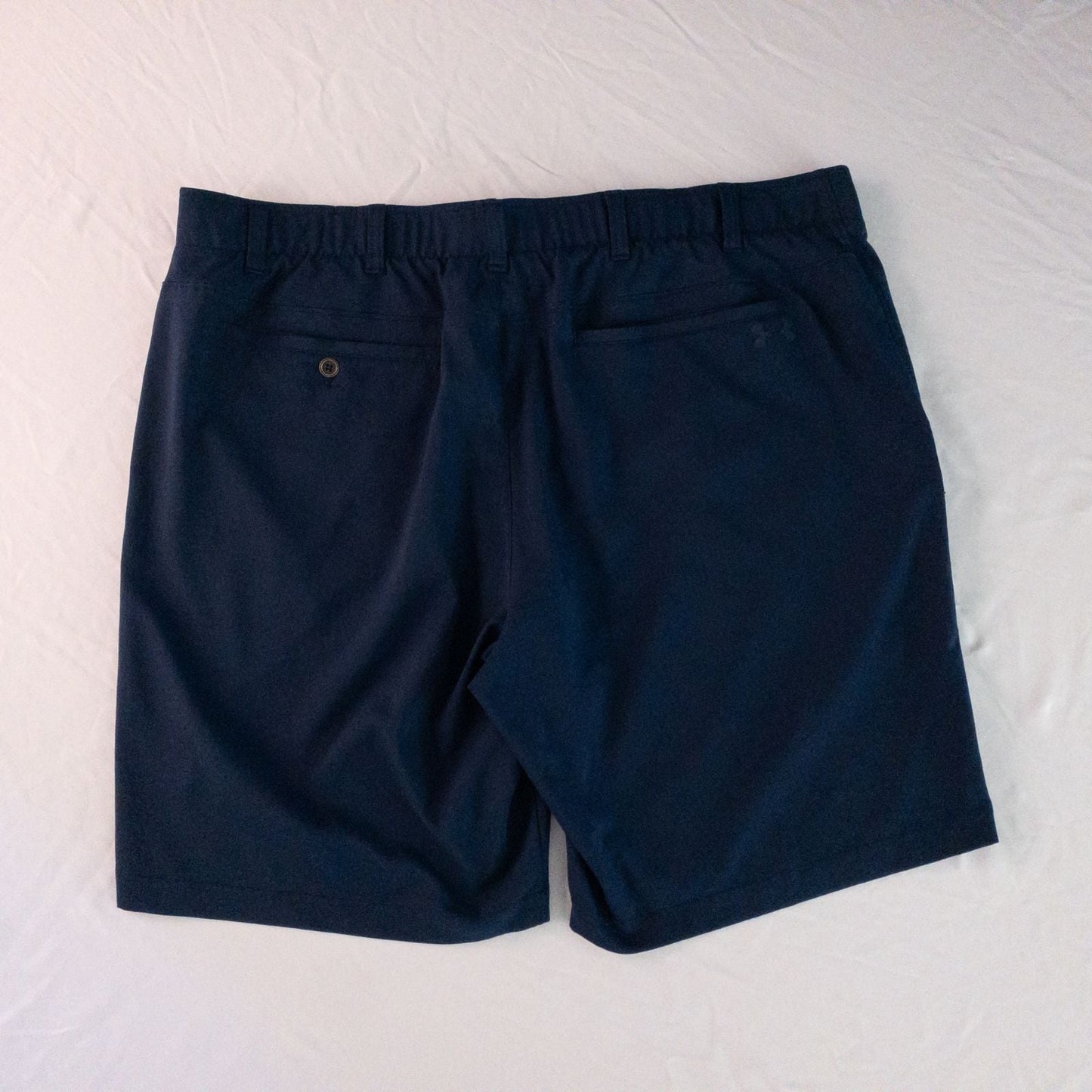 Under Armour navy men's shorts laid flat showing front and back views with button and logo details image 6