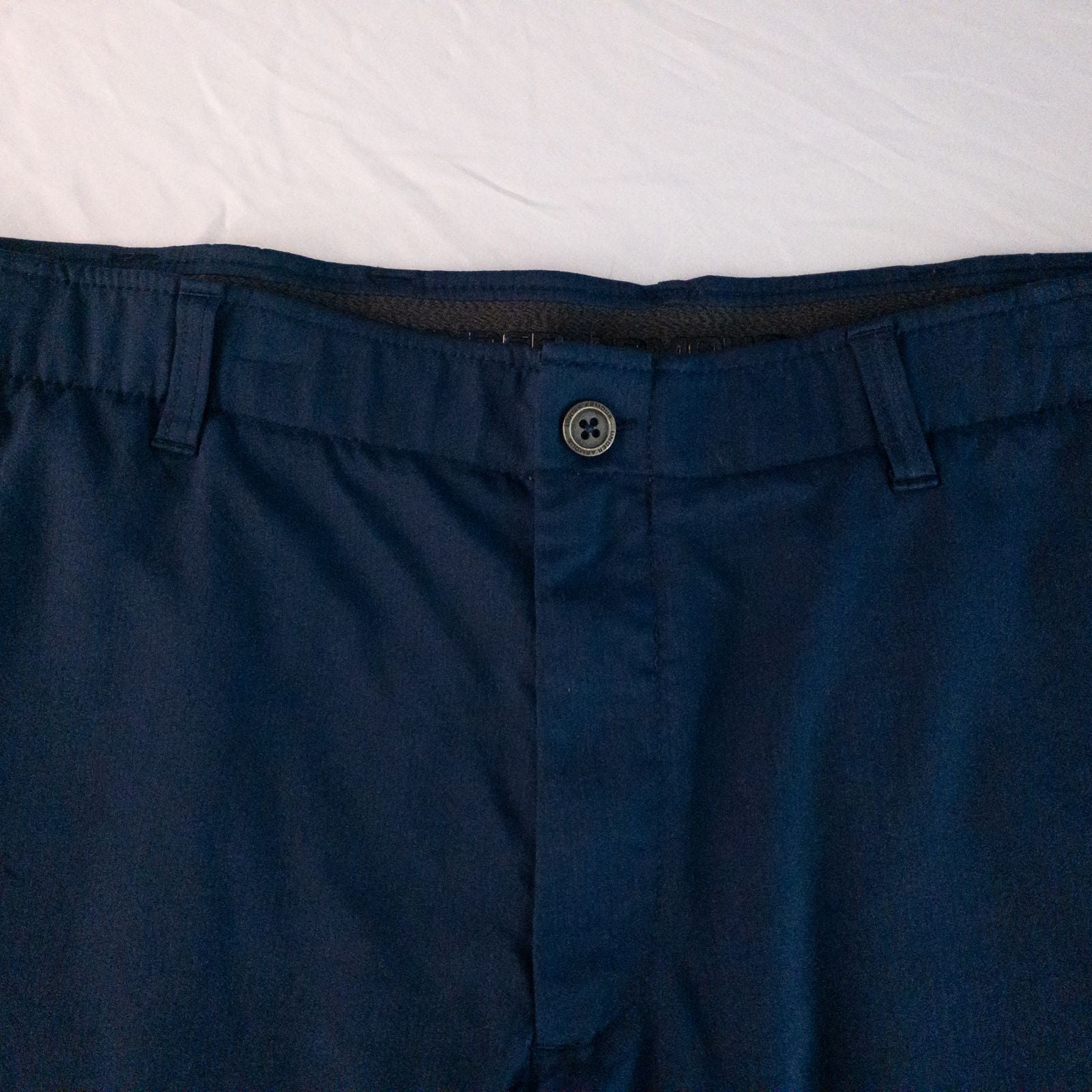 Under Armour navy men's shorts laid flat showing front and back views with button and logo details image 2