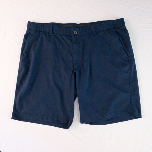 Under Armour navy men's shorts laid flat showing front and back views with button and logo details