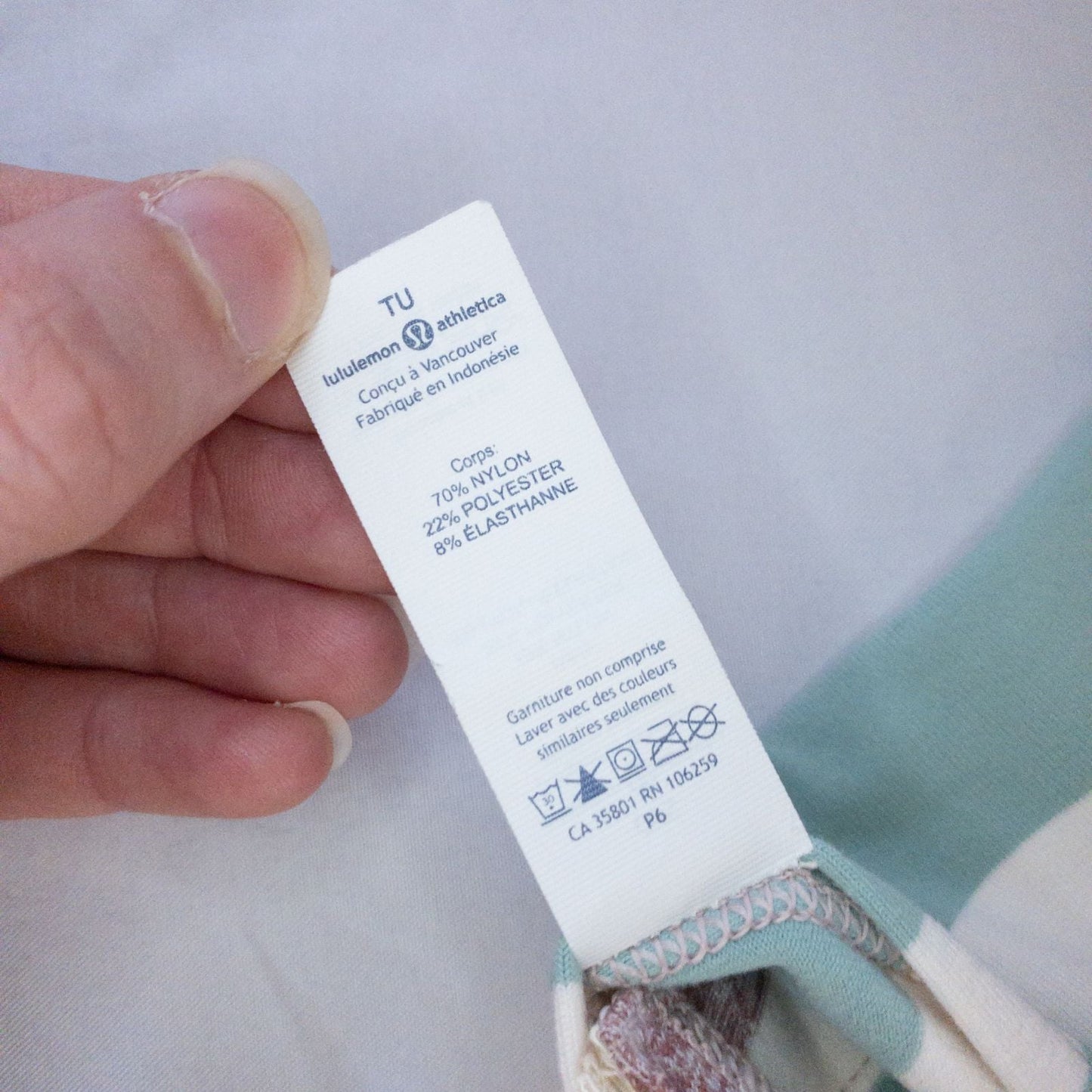 Lululemon striped neckwarmer scarf in white pink green tones displayed on a white mannequin head and laid flat showing snap closure image 11