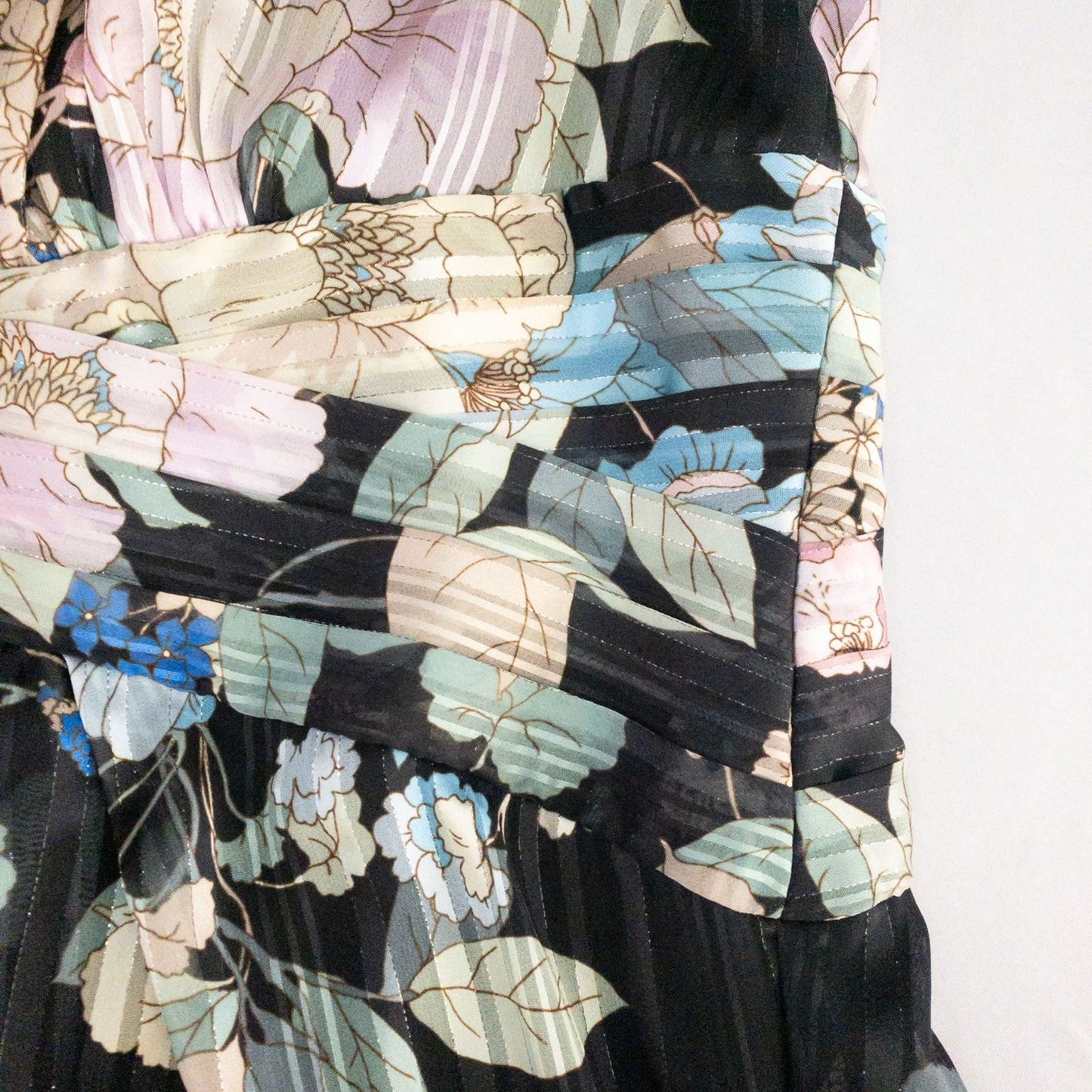 Adrianna Papell black floral maxi dress with twisted front detail hanging on clear hanger in front of white background image 10
