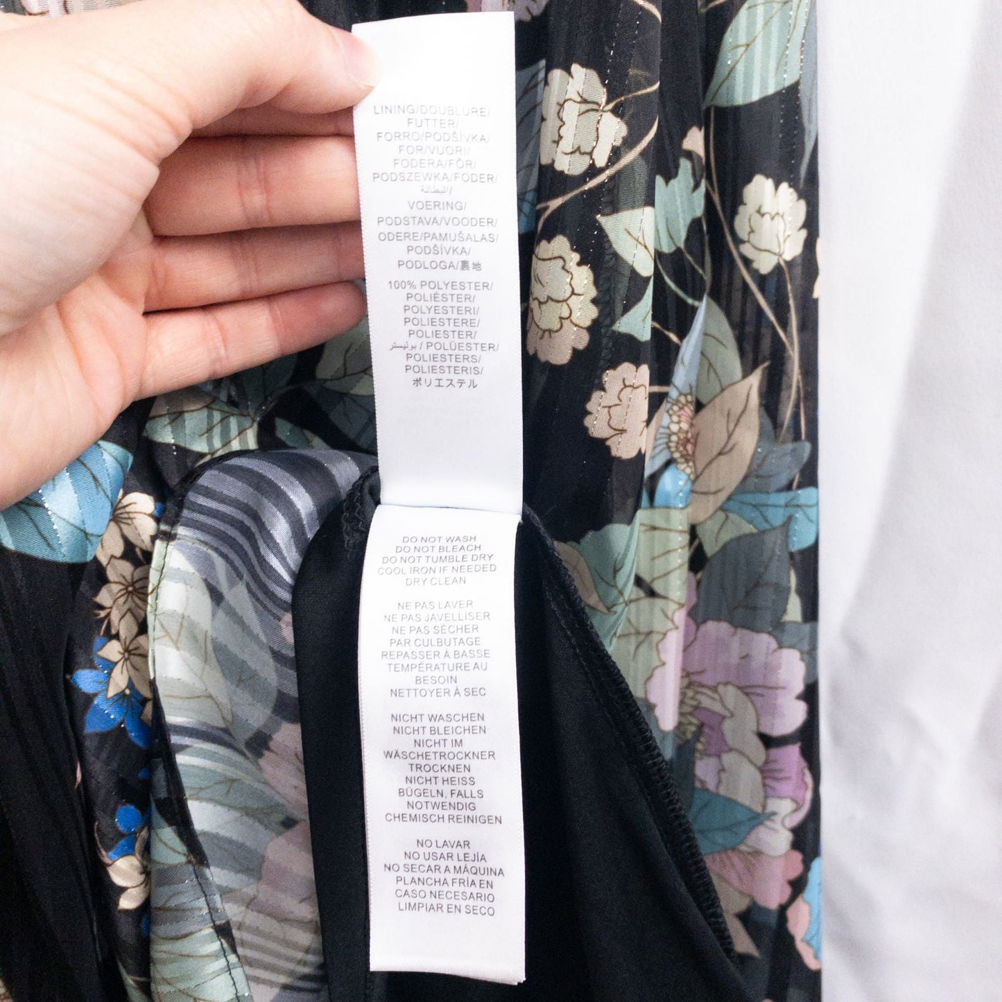 Adrianna Papell black floral maxi dress with twisted front detail hanging on clear hanger in front of white background image 14