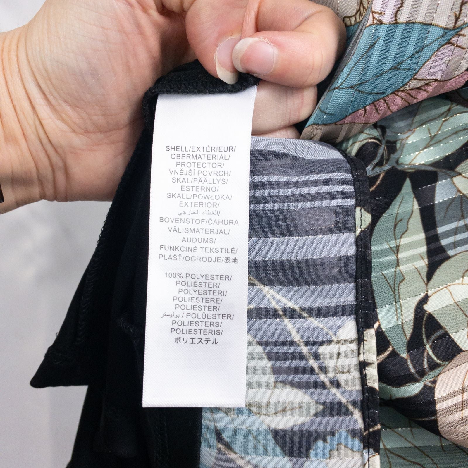 Adrianna Papell black floral maxi dress with twisted front detail hanging on clear hanger in front of white background image 13