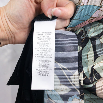 Adrianna Papell black floral maxi dress with twisted front detail hanging on clear hanger in front of white background image 13