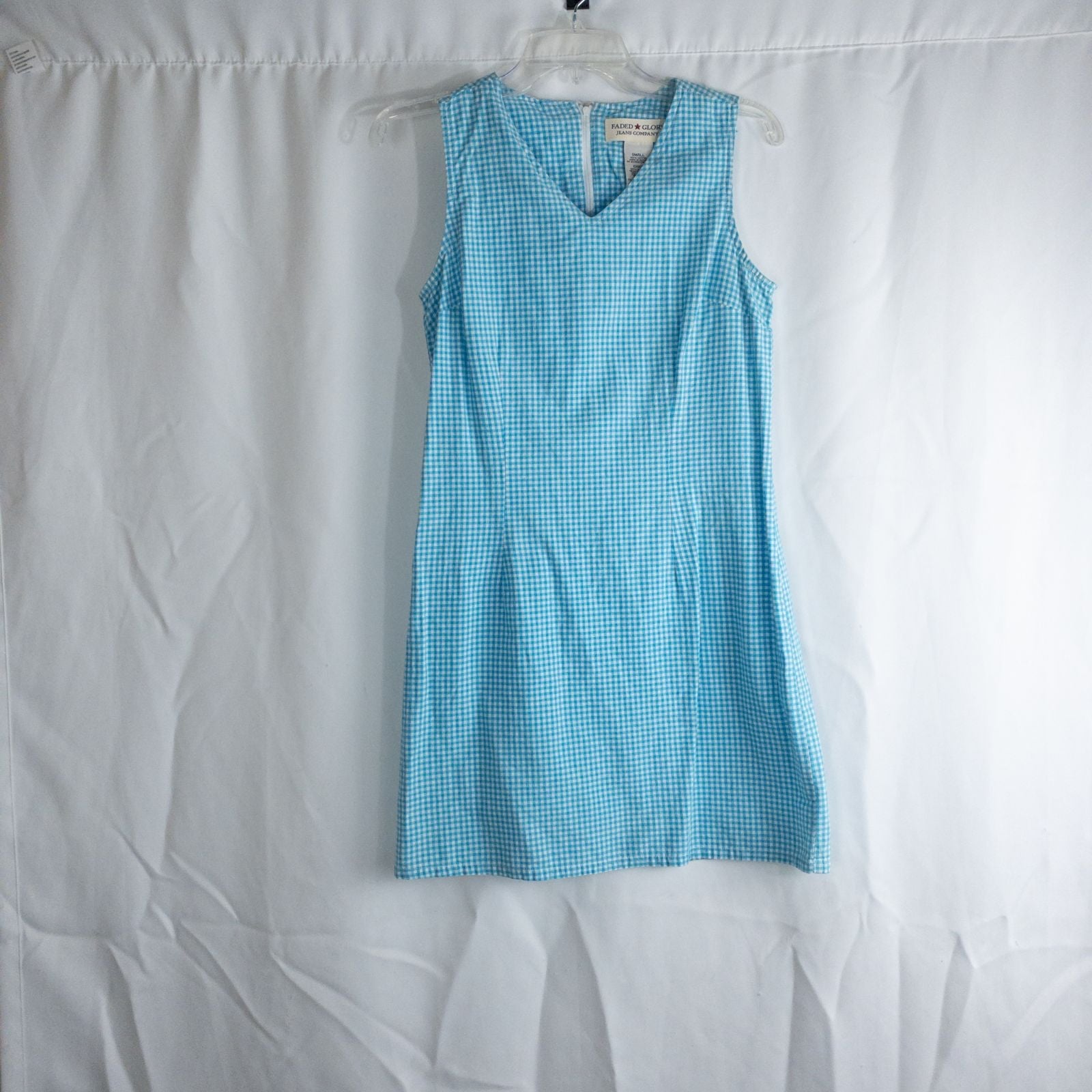 Faded Glory vintage blue and white gingham sleeveless dress with v-neck and back zipper on clear hanger against white background