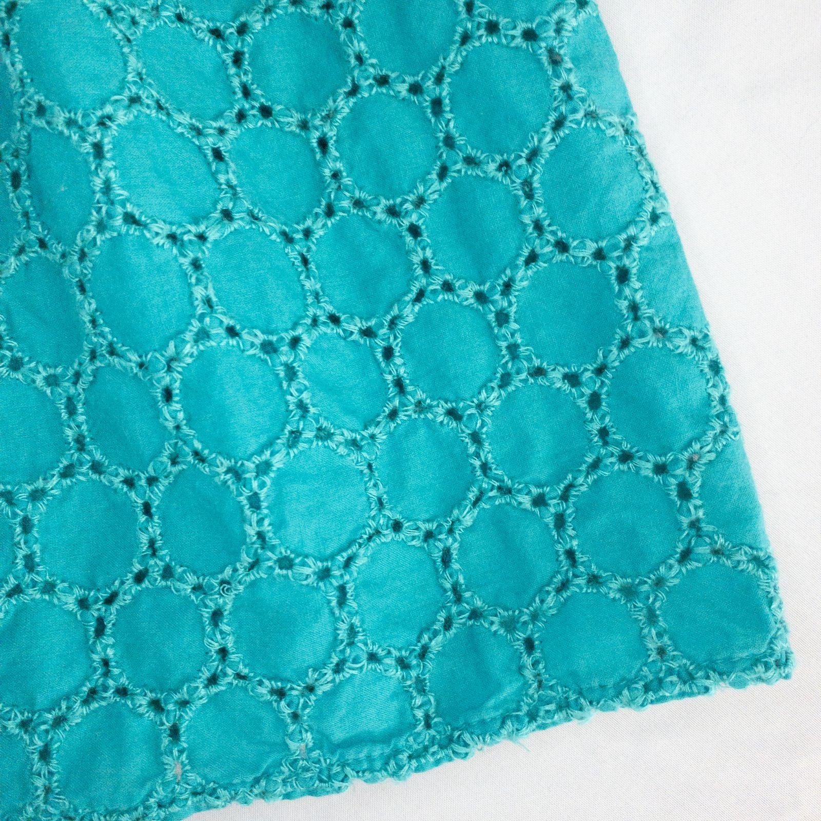 Old Navy teal green doily pattern sleeveless summer dress with gathered waist and concealed back zipper hanging on a clear hanger against a white cloth background image 4