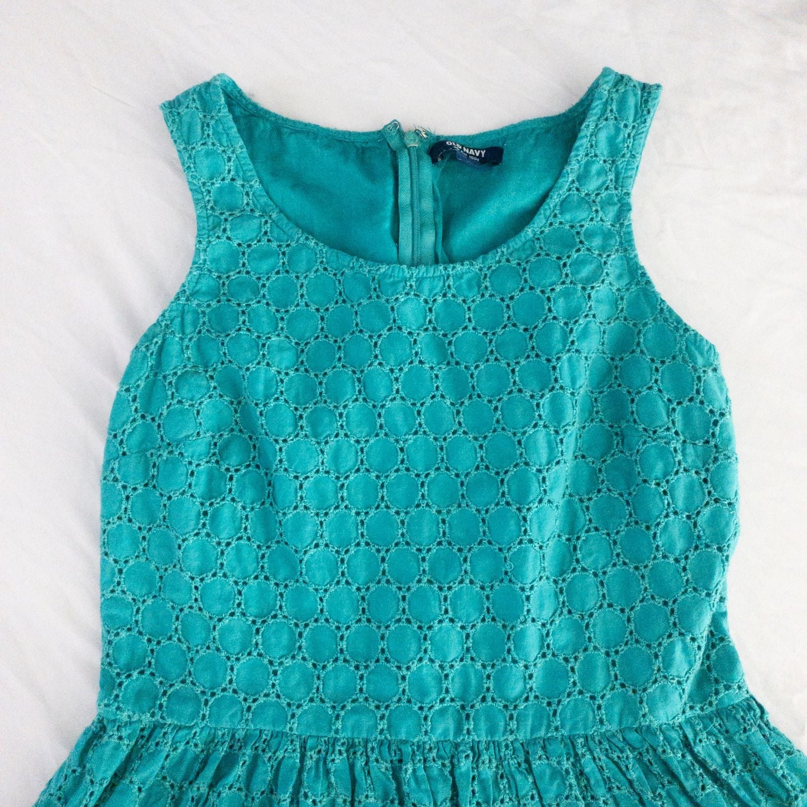 Old Navy teal green doily pattern sleeveless summer dress with gathered waist and concealed back zipper hanging on a clear hanger against a white cloth background image 3