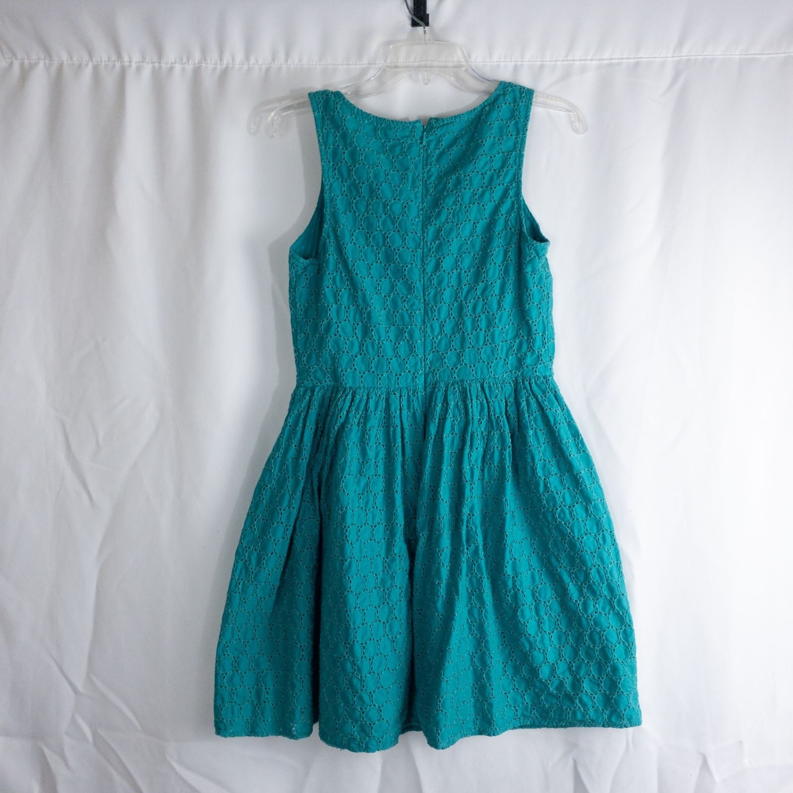 Old Navy teal green doily pattern sleeveless summer dress with gathered waist and concealed back zipper hanging on a clear hanger against a white cloth background image 5
