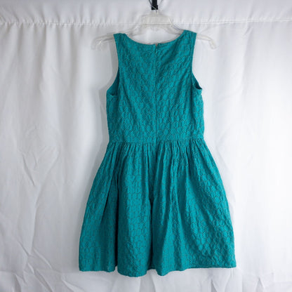 Old Navy teal green doily pattern sleeveless summer dress with gathered waist and concealed back zipper hanging on a clear hanger against a white cloth background image 5