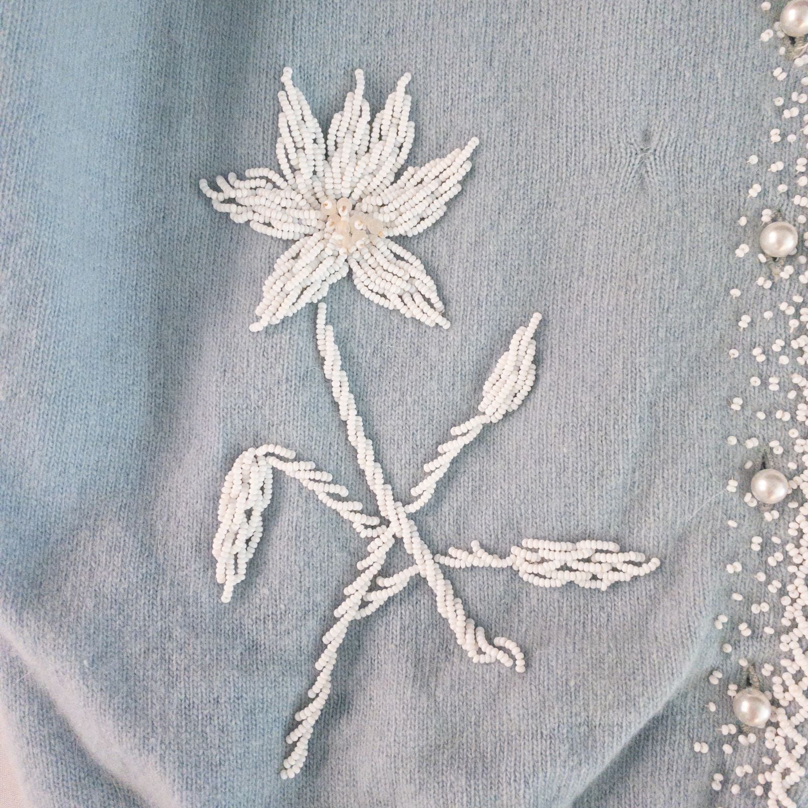 Stewarts pastel blue vintage cardigan with white bead floral embellishments and pearl buttons on a hanger image 3