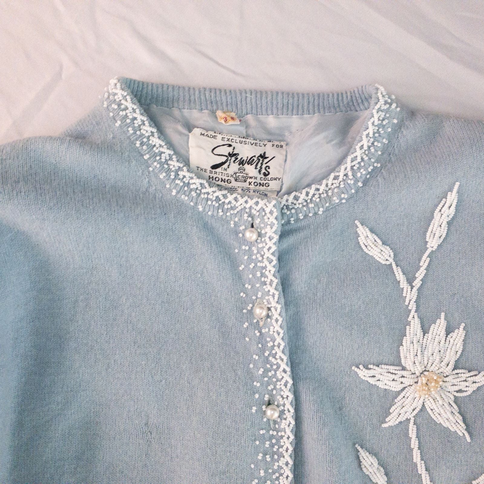 Stewarts pastel blue vintage cardigan with white bead floral embellishments and pearl buttons on a hanger image 2