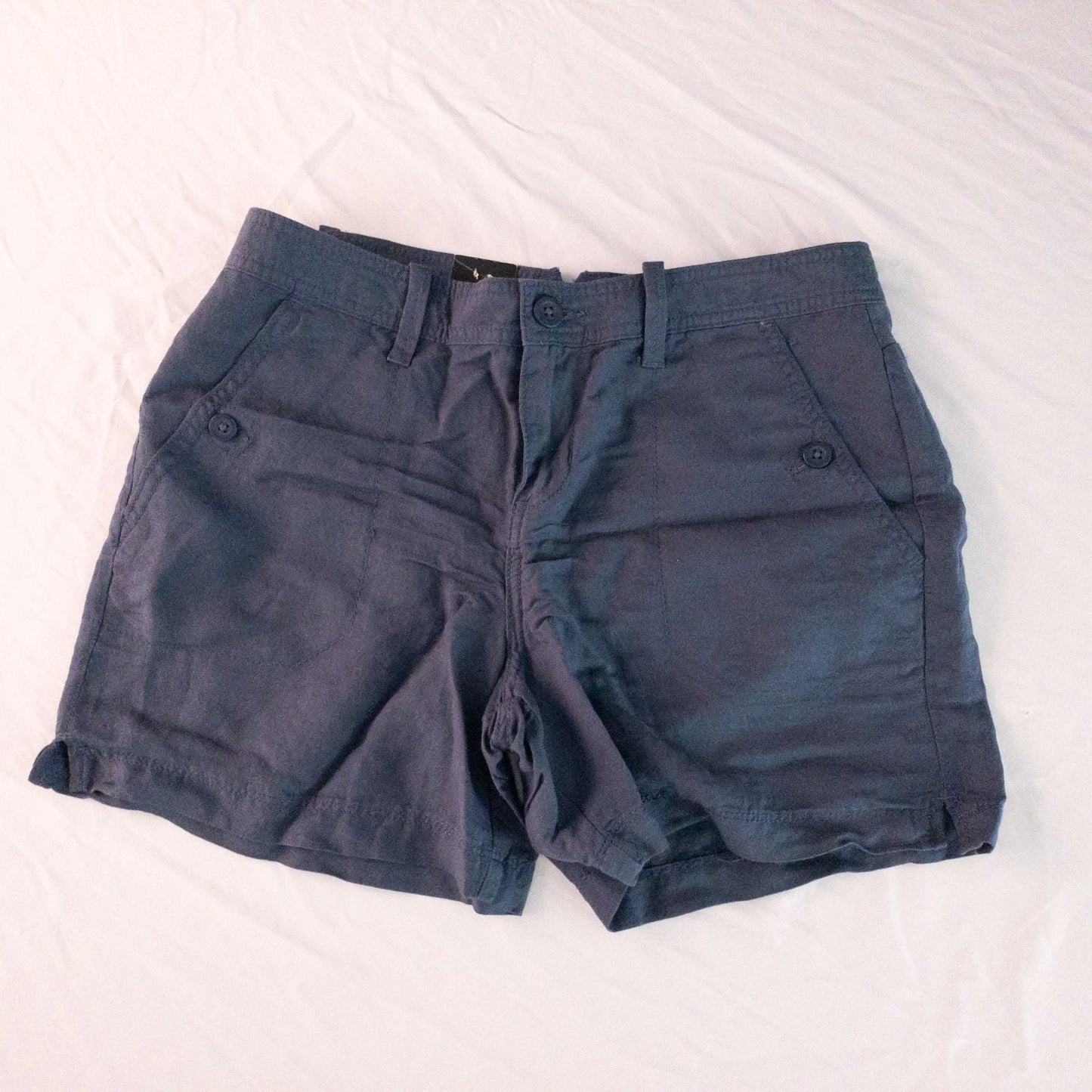 Calvin Klein blue linen shorts for women, size 4, with button closure and belt loops, front and back pockets, shown laid flat.