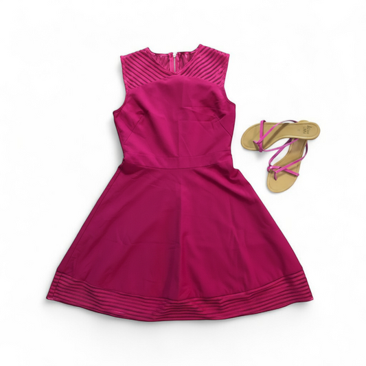 Pink sleeveless dress with sheer striped mesh panels on neckline and hem laid flat on wood floor front on white muslin photography backdrop