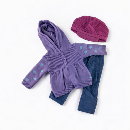 American Girl doll outfit with purple polka dot hoodie, blue pants, and magenta hat laid flat with visible light marks front on white muslin photography backdrop