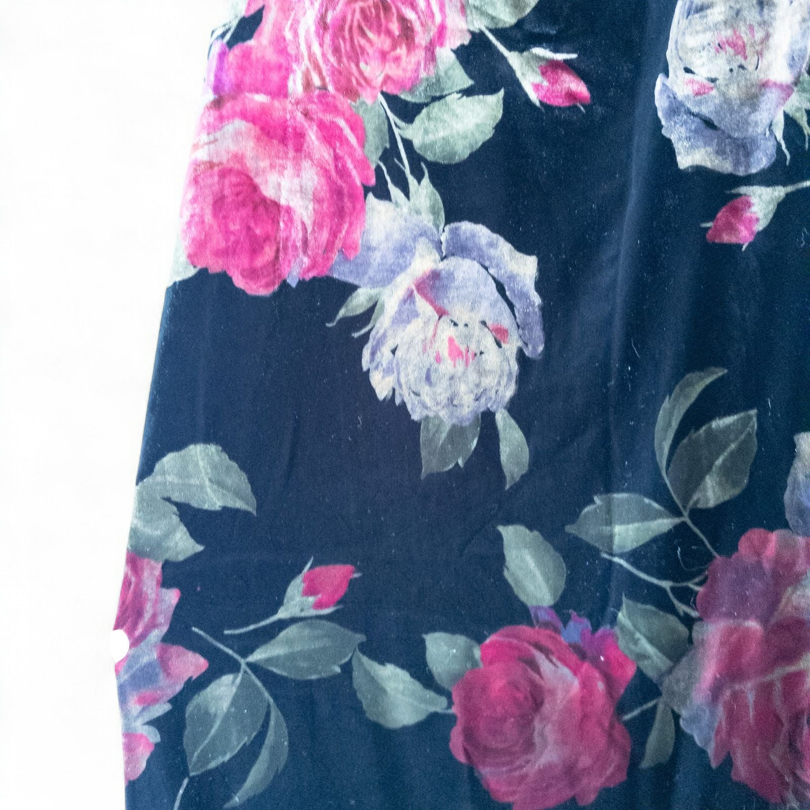 Vintage Jeffrey & Dara red rose velvet evening dress size 12 hanging in front of bookshelves showcasing black velvet fabric with red and purple rose floral pattern and cowl neckline. image 4