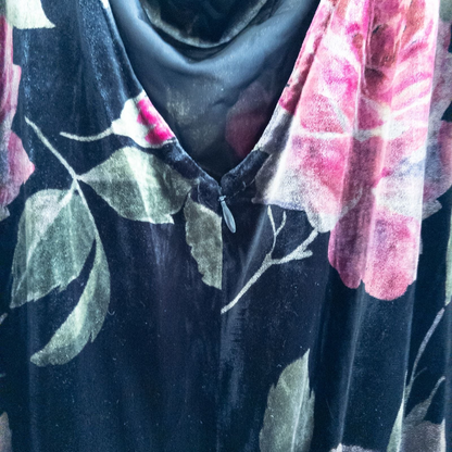 Vintage Jeffrey & Dara red rose velvet evening dress size 12 hanging in front of bookshelves showcasing black velvet fabric with red and purple rose floral pattern and cowl neckline. image 7